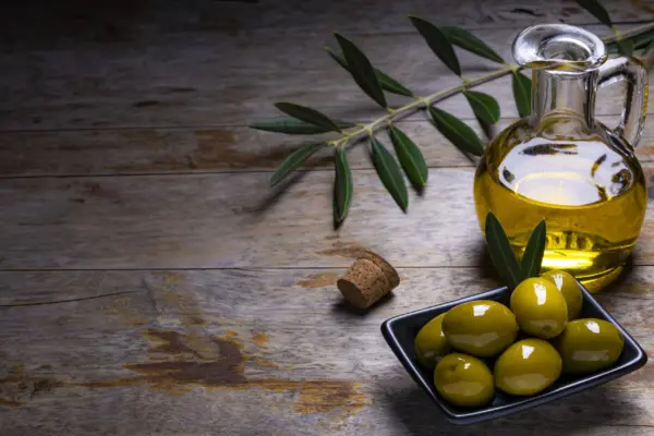 Tasty looking olives extra virgin oil olive leafs dark wooden backgorund